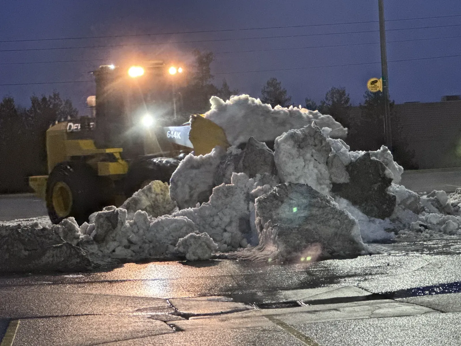 Wheel loader working a snow pile under its work lights at night