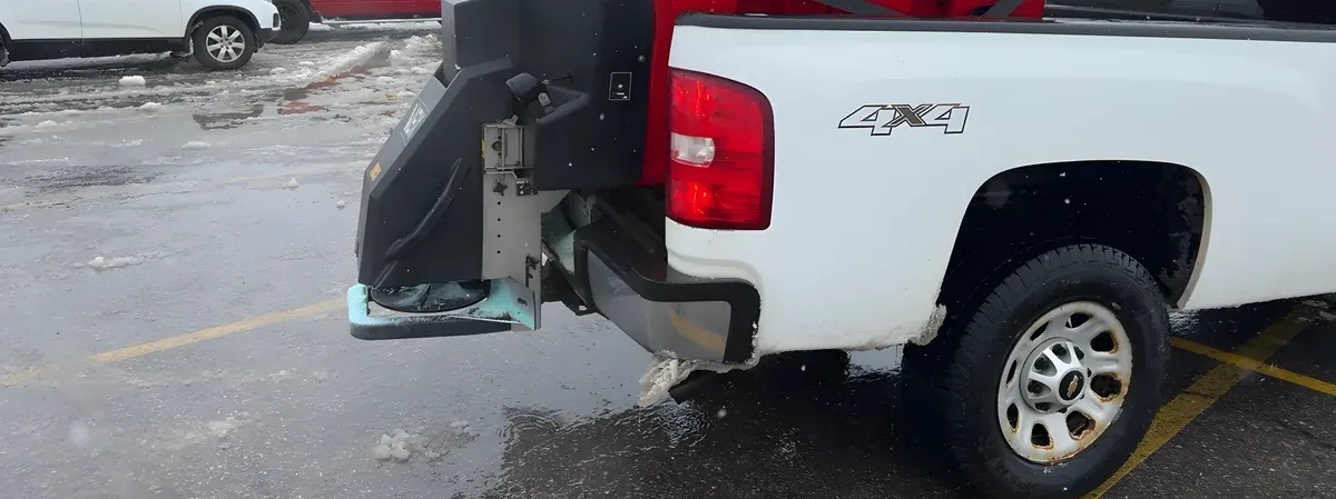 White pickup with a BOSS spreader in a parking lot